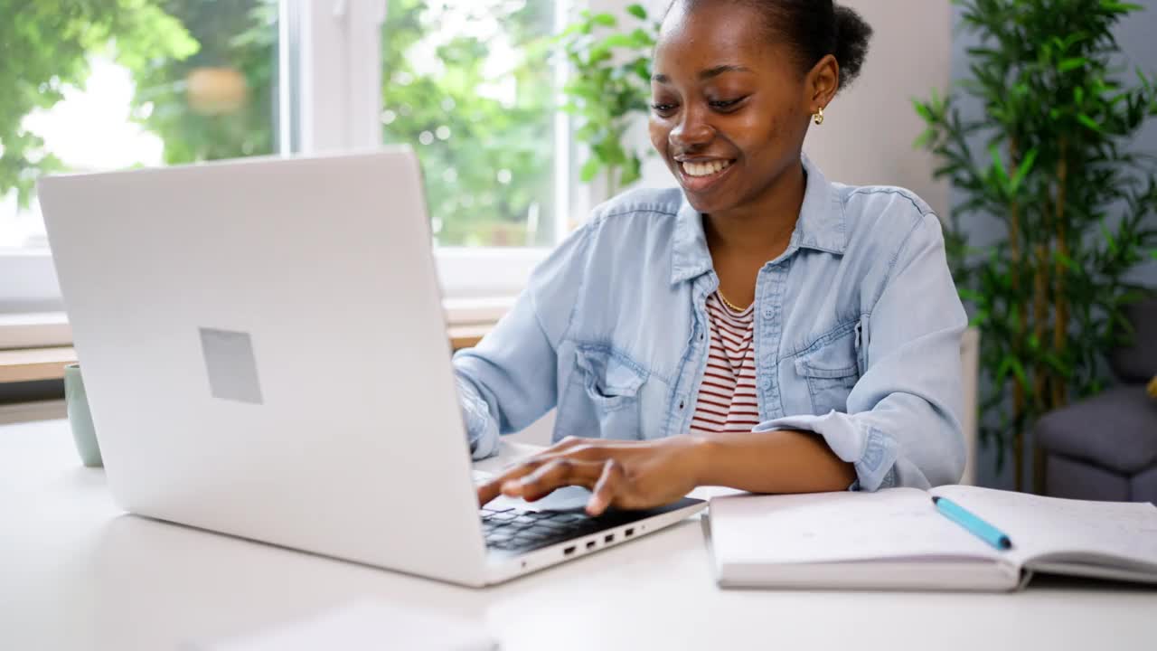 年轻的黑人女性在家办公室用笔记本电脑工作视频下载
