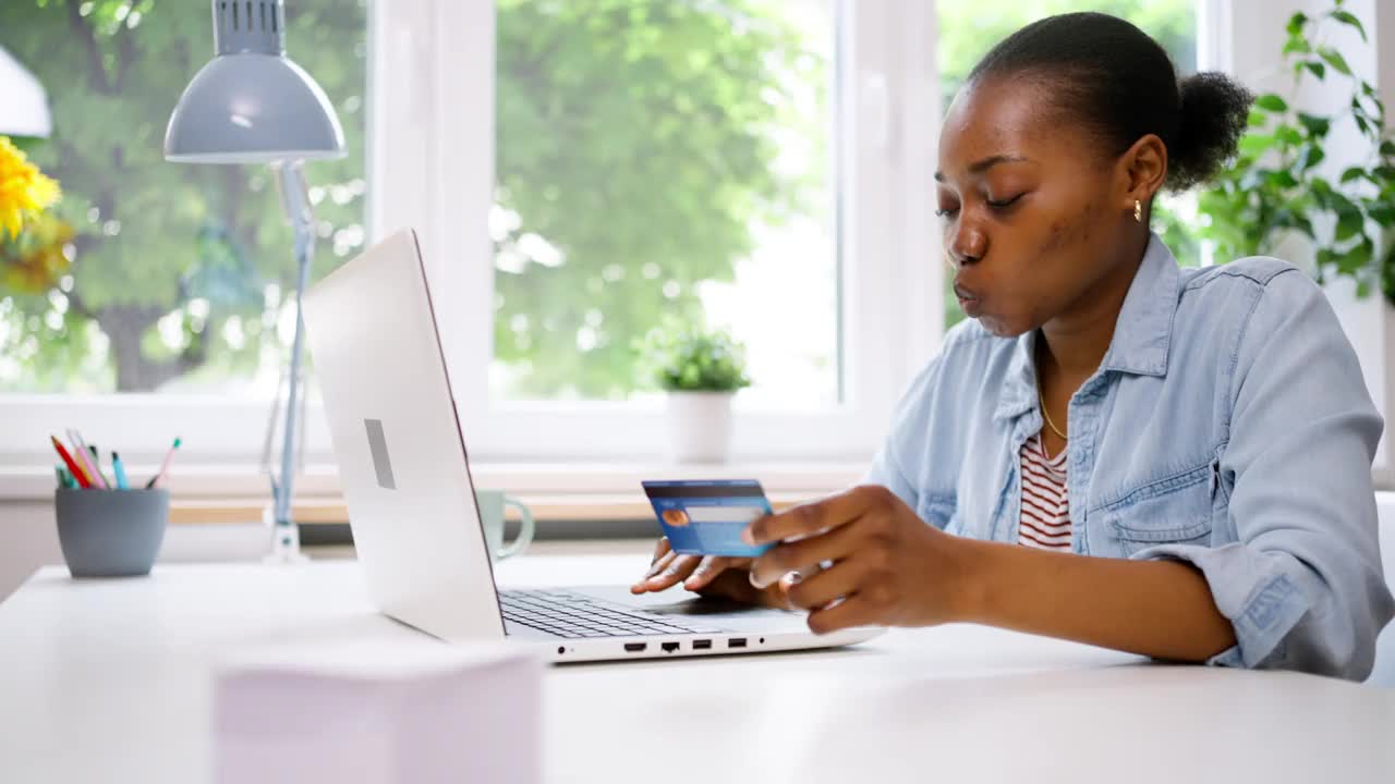 年轻的黑人女性用信用卡在笔记本电脑上网购视频素材