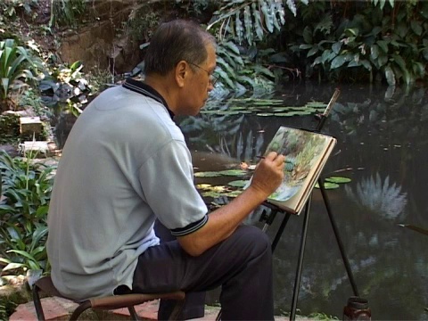 画家在池塘边画水彩画。视频下载