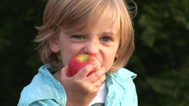 一个小男孩在吃苹果。视频下载