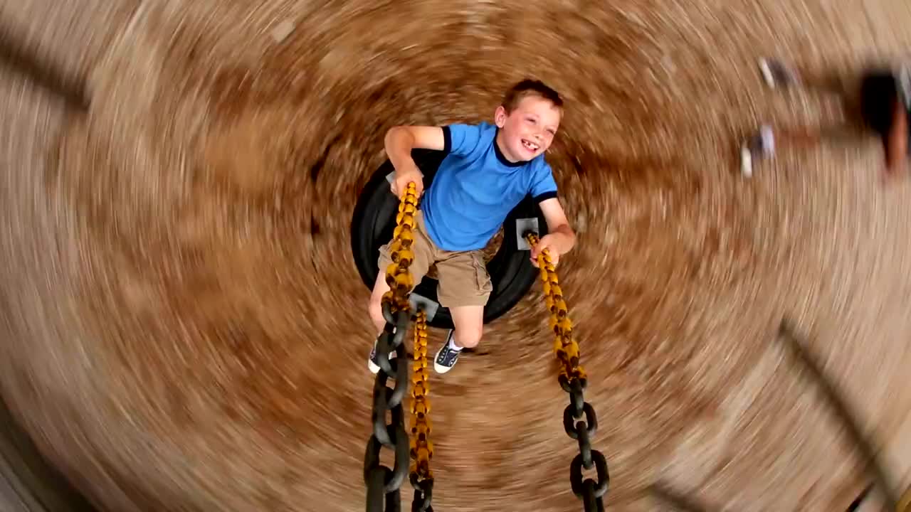 一个小男孩在学校操场上旋转轮胎视频下载