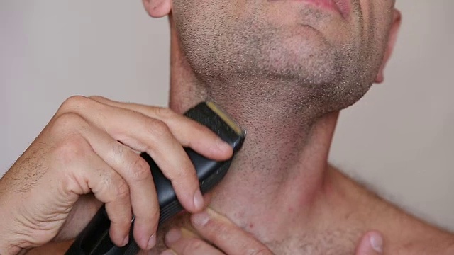 一个赤膊男子用电动剃须刀剃须的极端特写视频素材