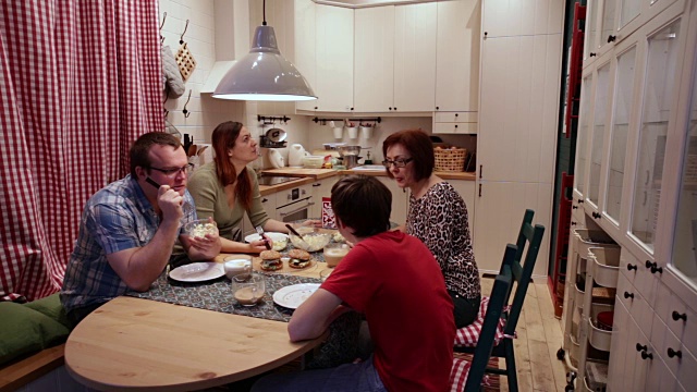 一家四口坐在厨房的桌子旁视频素材