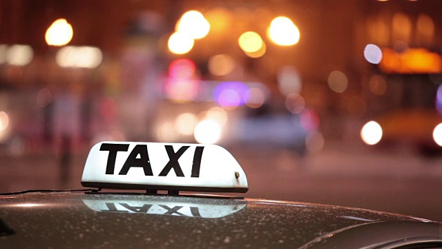 在大城市的夜晚街道上，闪亮的出租车铭文在过往的汽车上视频购买