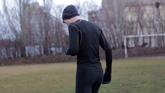 一个年轻人在寒冷的秋天跑步热身。视频下载