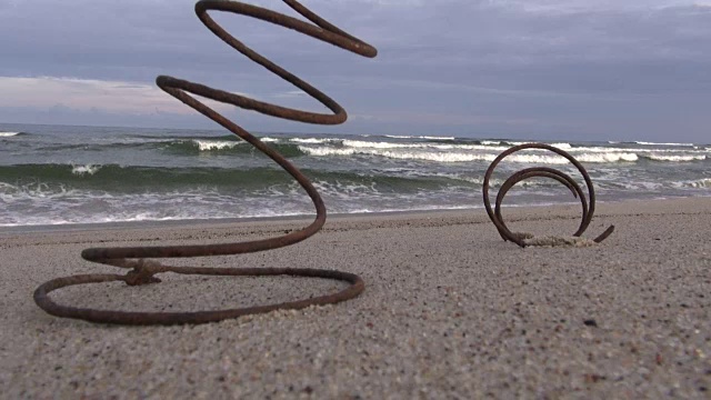 陈旧生锈的金属弹簧在海边沙滩和海浪上视频下载