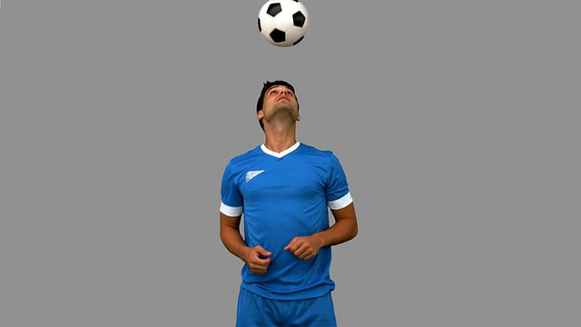 一名男子在灰色屏幕上用头玩弄足球视频素材