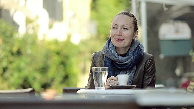 在户外咖啡馆喝咖啡的年轻女子视频素材