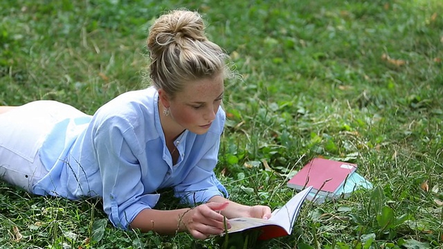 年轻女子在草地上看书视频素材
