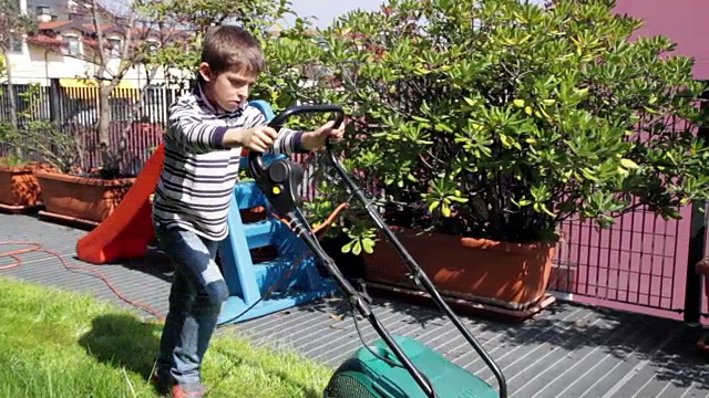孩子用割草机在花园里工作视频素材