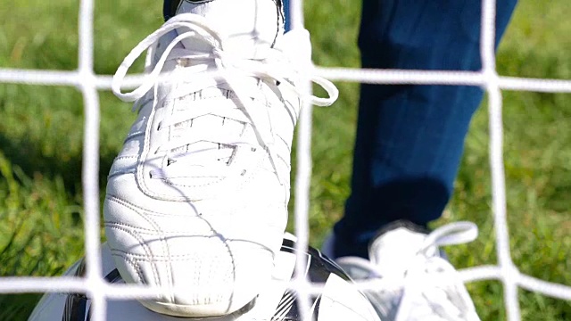 足球运动员系好他的足球靴，足球网在前面视频下载