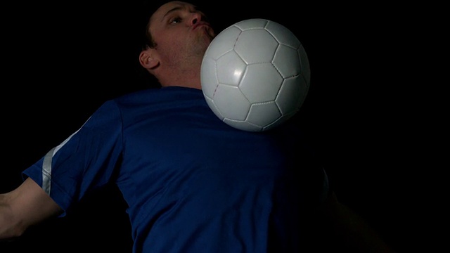 足球运动员用胸部在黑色背景上控制球视频下载