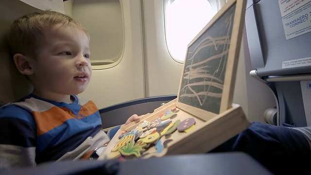 飞机上的男孩在黑板上用粉笔画画视频下载