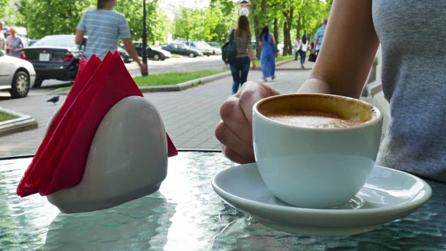 女人喝咖啡。玻璃杯在杯子旁边视频素材