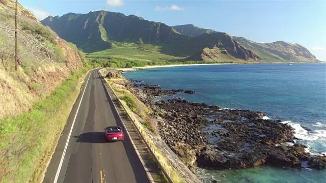 一對夫婦開著紅色敞篷車沿著夏威夷海岸公路行駛視頻素材