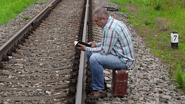 一个人坐在火车旁的箱子上看书视频下载