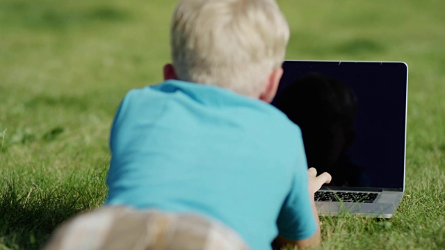 男孩在草地上用笔记本电脑视频素材