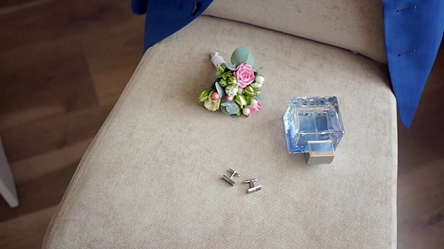 优雅的男士婚礼配件，马桶水和纽扣孔躺在椅子上，他的夹克挂在椅背上视频素材