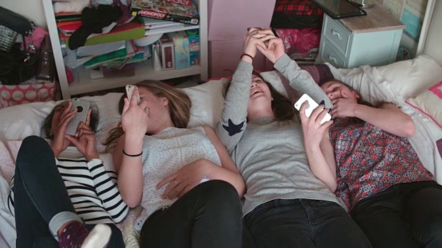 十几岁的女孩躺在床上用手机在家视频素材