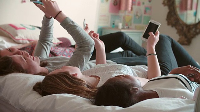 十几岁的女孩躺在床上用手机在家视频素材