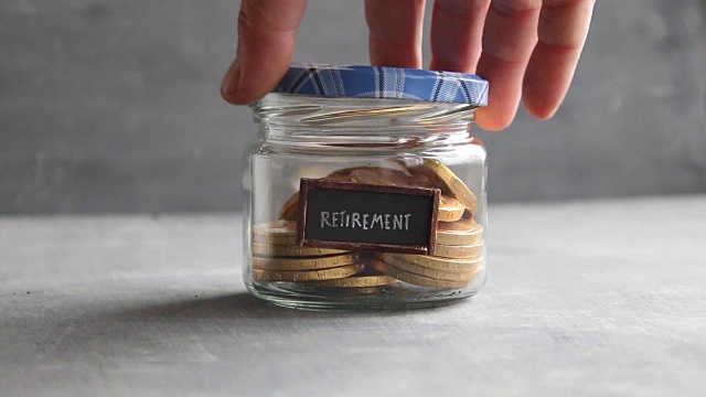 退休标签和硬币装在玻璃罐里。为养老储蓄基金养老的想法。视频素材