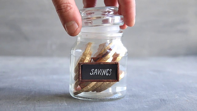 硬币装在玻璃钱罐里，贴有储蓄标签，理财理念。视频素材