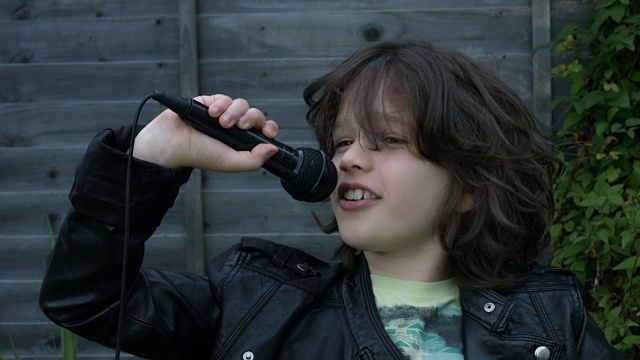 一个可爱的孩子在外面用麦克风唱歌的4k镜头视频下载