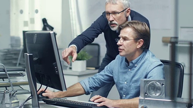 在繁忙的工程局两位高级工程师讨论个人电脑技术问题。他们的办公室看起来简约而现代。视频素材