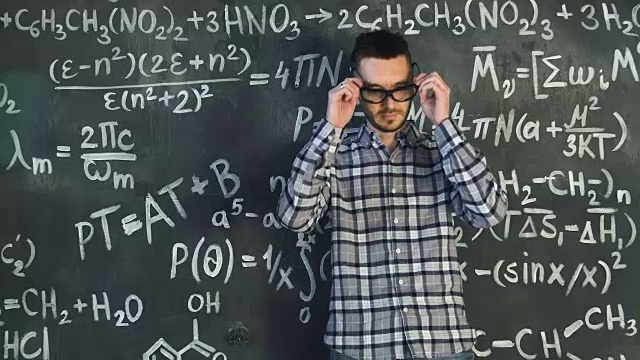 年轻的科学家在化学和数学方程式墙房间内部擦他的眼镜视频素材