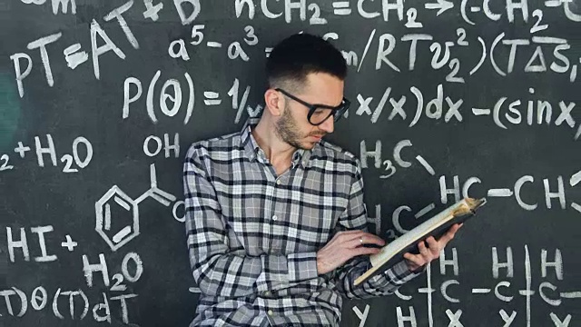 年轻的科学家在读化学和数学方程式的书，墙壁房间内部视频素材