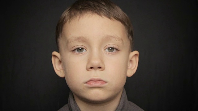 一个男孩的肖像特写在一个黑色的背景。全高清视频视频素材