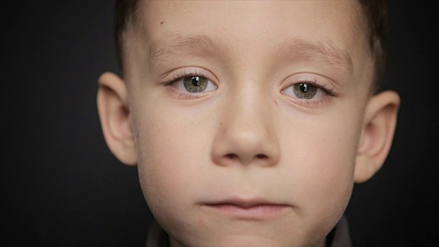 一个男孩的肖像特写在一个黑色的背景视频素材