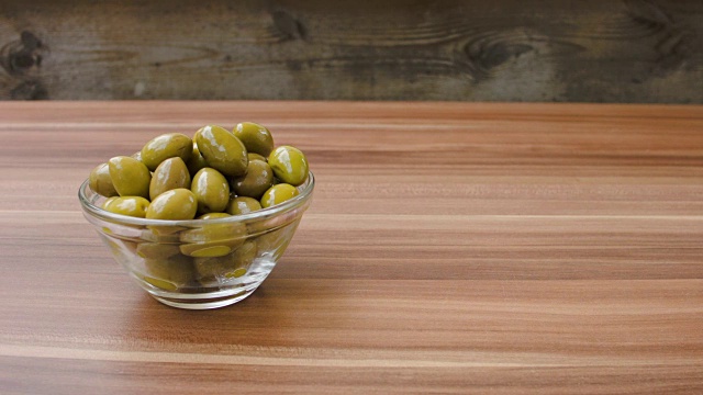 木桌子上的玻璃碗里盛着绿橄榄视频素材