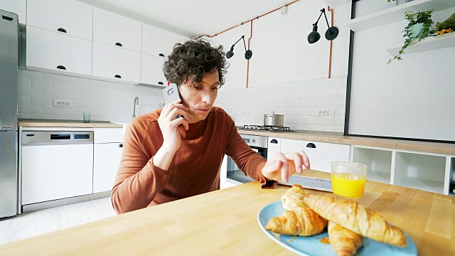 一个男人一边吃早餐一边打电话。视频素材