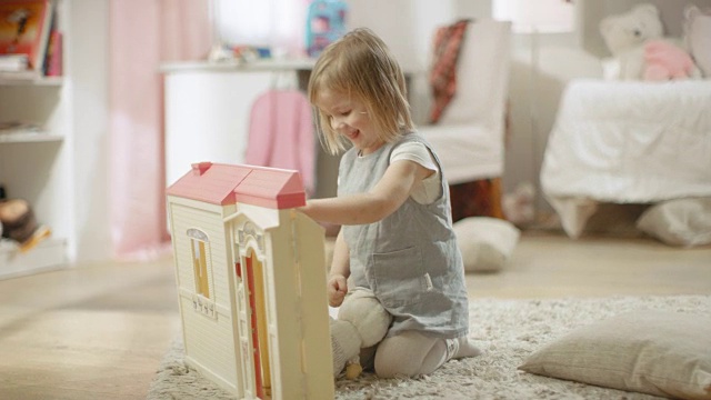 快乐的小女孩跑向娃娃屋，开始玩娃娃屋。视频下载