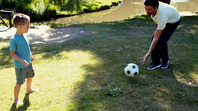 爸爸和儿子在公园里踢足球视频下载