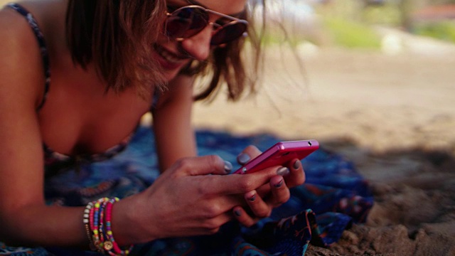 快乐的年轻女子在沙滩上发短信视频下载