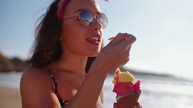 年轻女子在海滩上吃冰淇淋视频下载