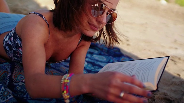 年轻女子在夏天的海滩上看书视频下载