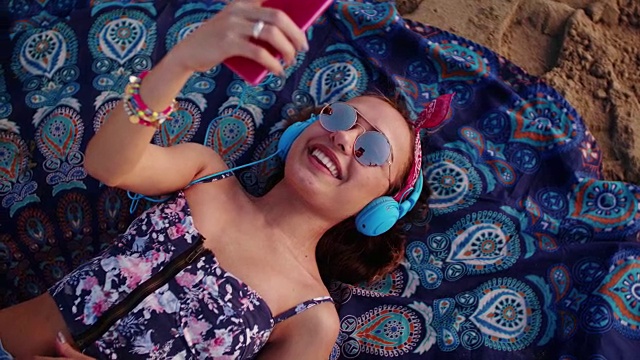 年轻女子戴着耳机在海滩上听音乐视频下载