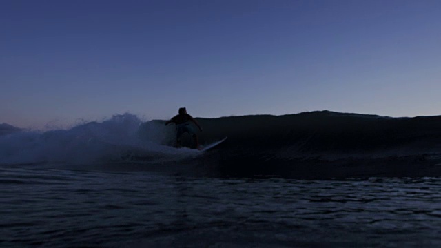 日落冲浪者剪影骑在蓝色的海浪视频素材