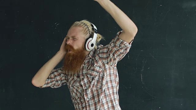 一个留着胡子的年轻人戴着耳机，一边听着黑色背景音乐一边跳舞视频下载