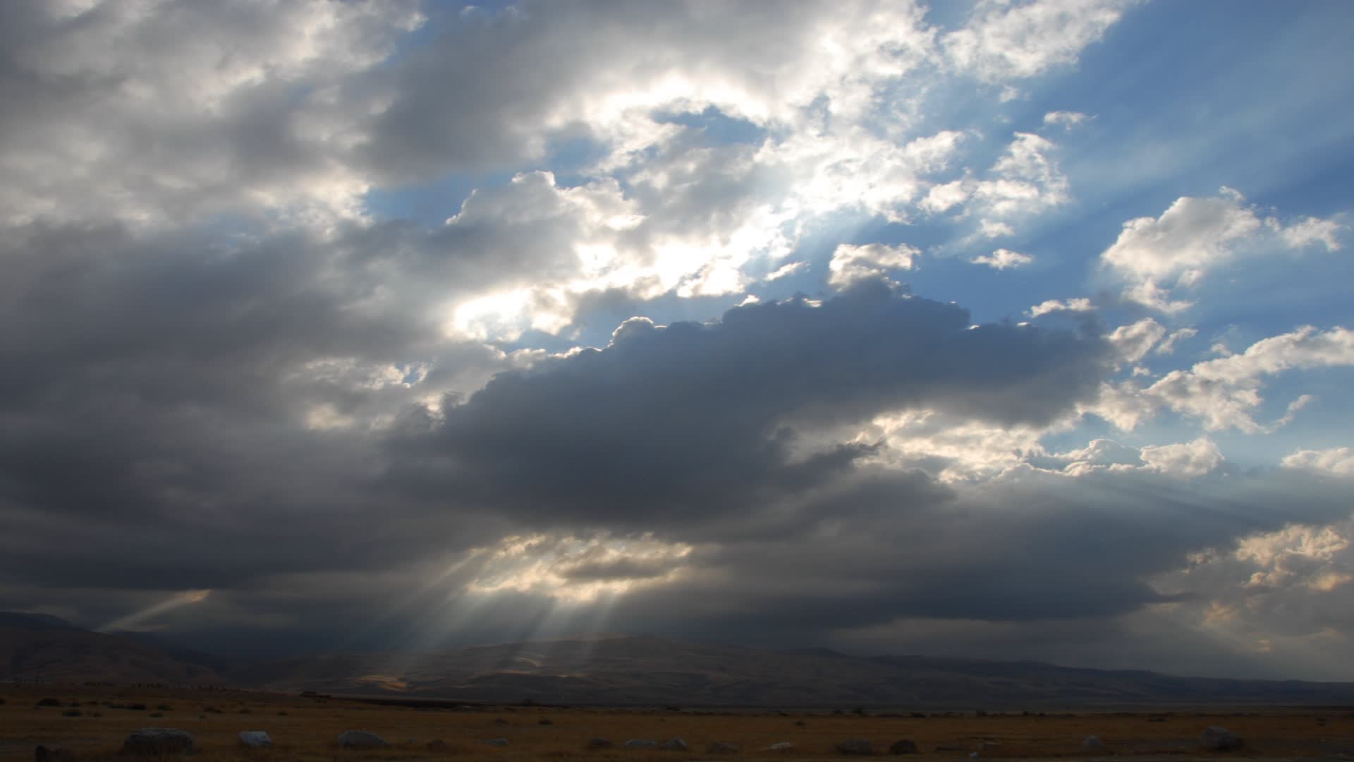 随着时间的推移，风暴云越过山脉，光束的阳光条纹前景平原。视频素材