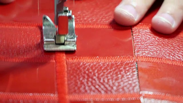 工厂生产的概念真皮制品。在缝纫机上缝合红色皮革视频下载