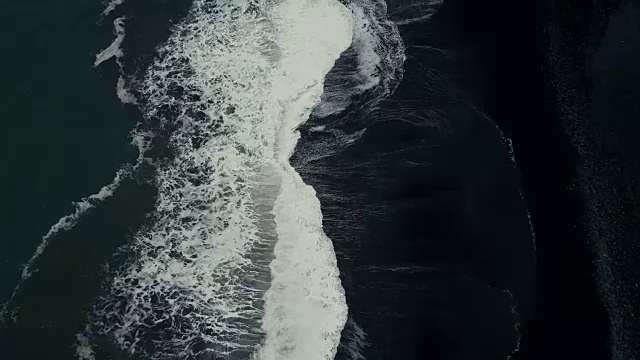 鸟瞰图与泡沫强大的海浪来海岸的黑色火山海滩在冰岛视频下载