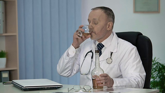 精疲力竭的男医生允许自己在辛苦工作一天后喝烈酒视频素材