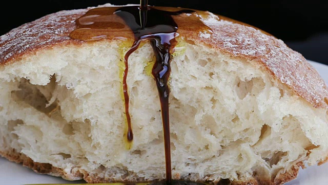 慢动作特级初榨橄榄油和香醋浇在面包上视频素材