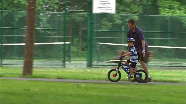 WS男子教男孩如何骑自行车在公园/ Fanwood，新泽西州视频素材
