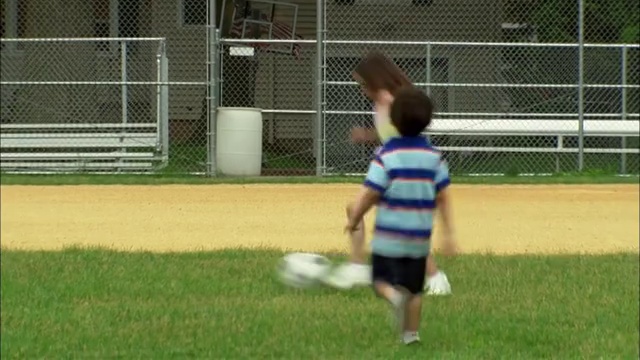 新泽西，范伍德，男孩和女孩在棒球场上踢足球视频素材