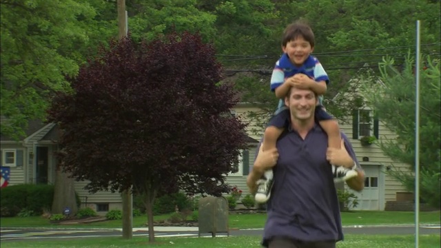 新泽西郊区公园/范伍德，一名男子扛着一个男孩视频下载